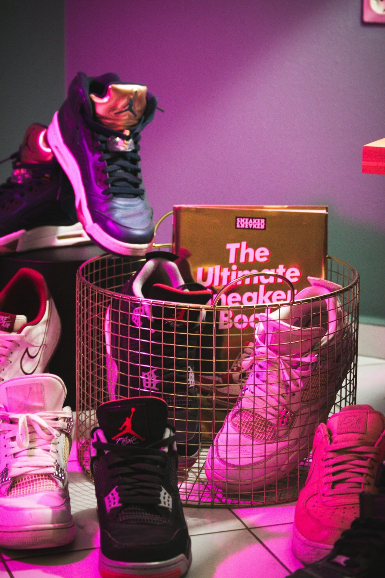 Various sneakers spread across the floor and in a basket