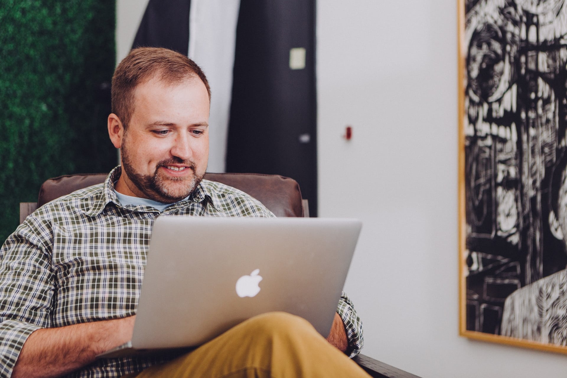 Mann mit Laptop in einem Sessel