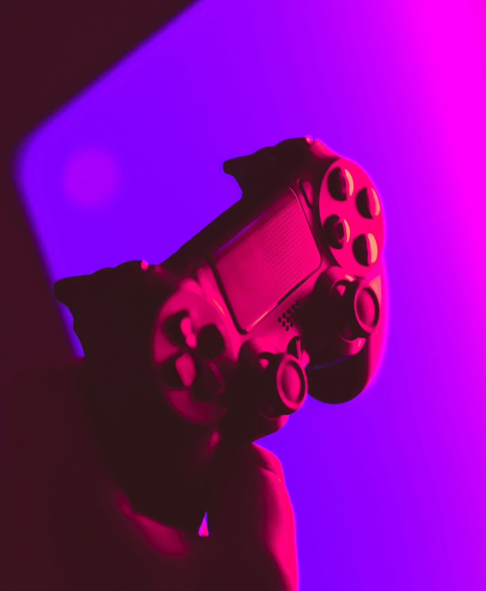 Gamepad in einer Hand vor violettem Hintergrund