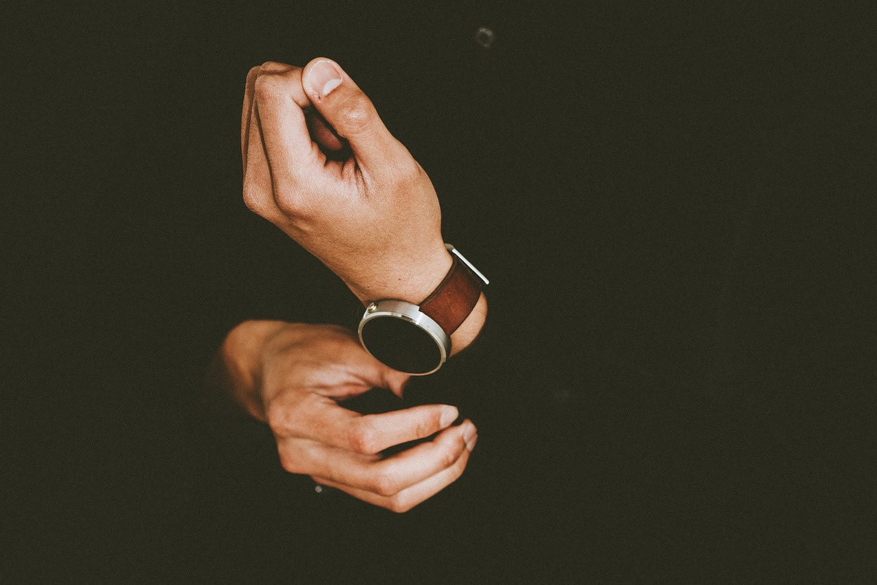 Armbanduhr am Handgelenk vor dunklem Hintergrund