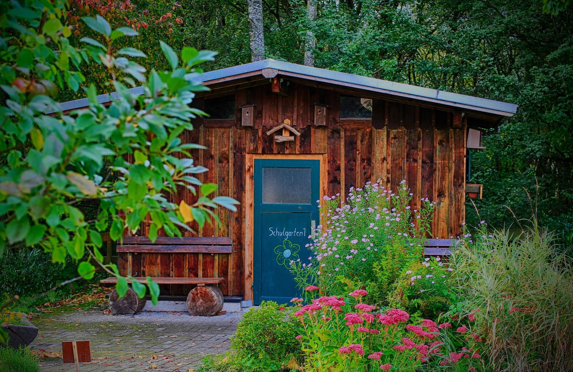 Kleines Holzhaus im Garten mit Blumenbeet