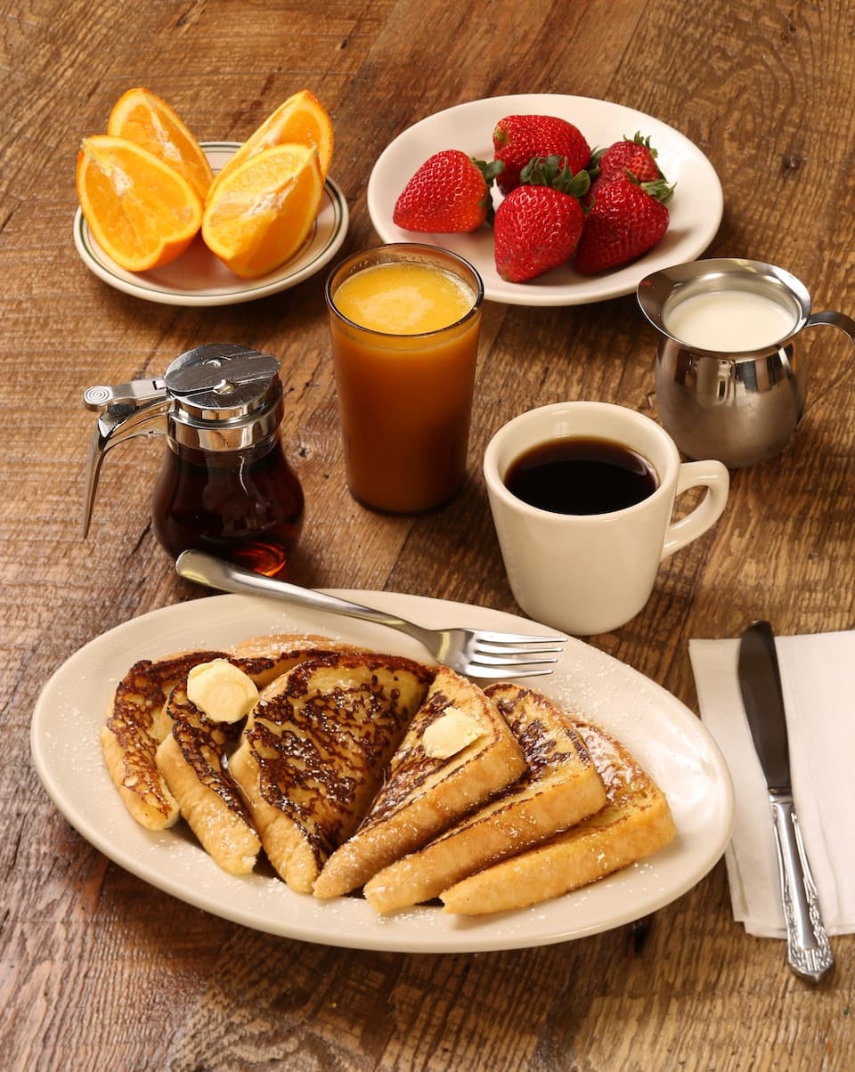 Frühstückstisch mit French Toast, Obst, Orangensaft und Kaffee